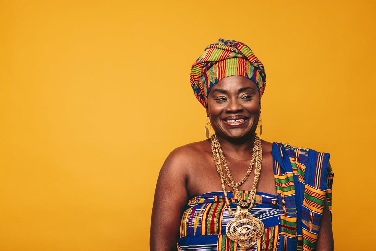 Smiling Ghanaian woman wearing colourful Kente cloth and golden jewellery
