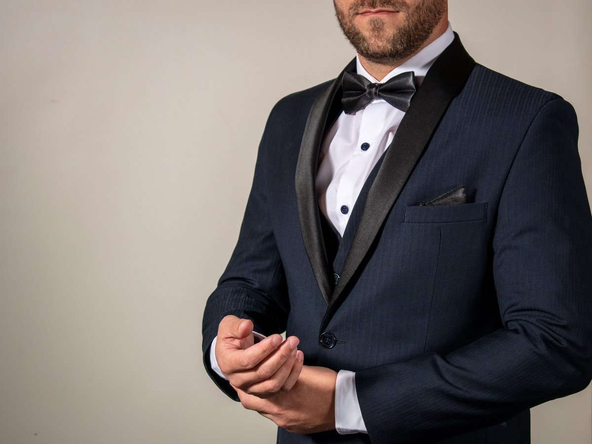 Business man in elegant wedding suit adjusting cufflinks studio portrait