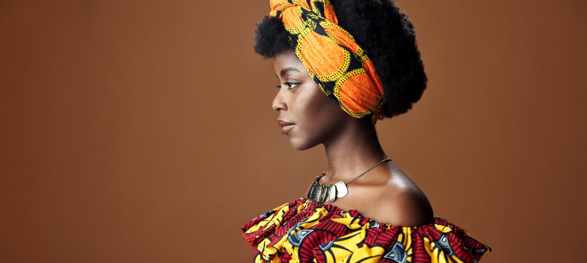 Confident African woman in traditional wrap outfit and head wrap studio portrait