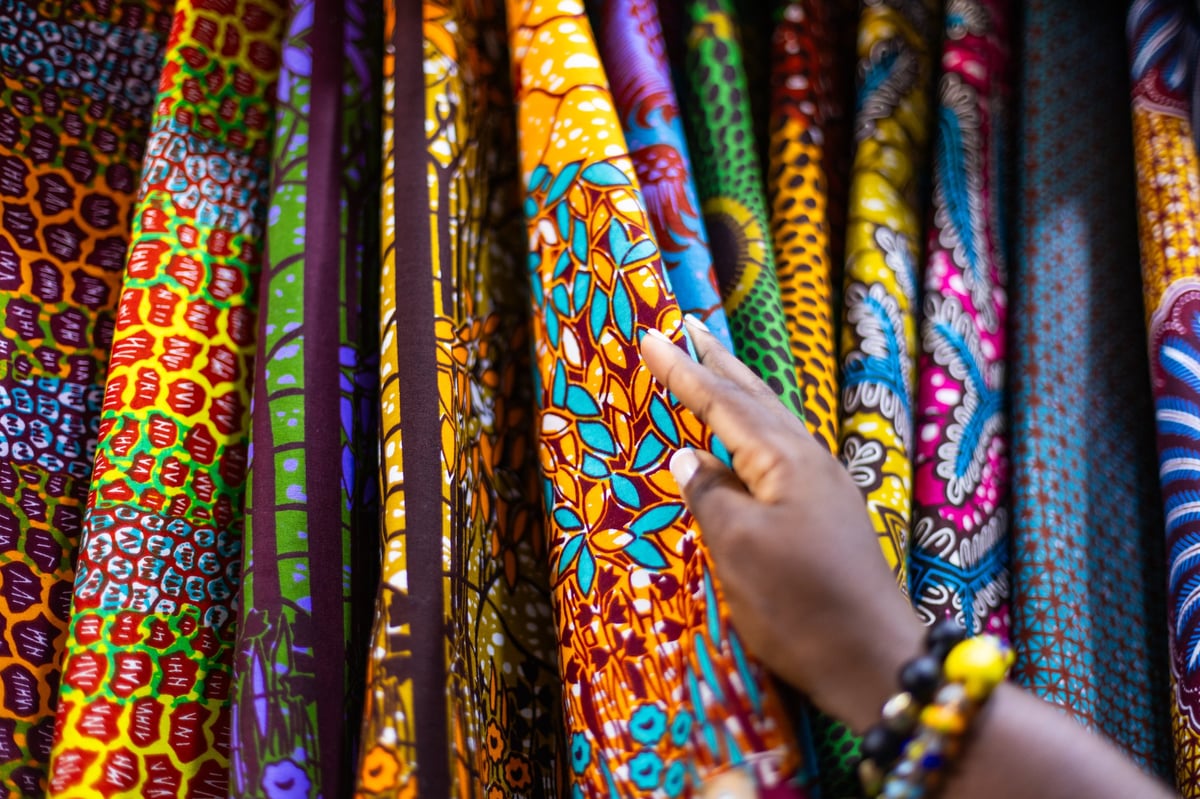 Small business owner of an African Print, Ankara fabric shop proudly displaying different kinds of textile prints
