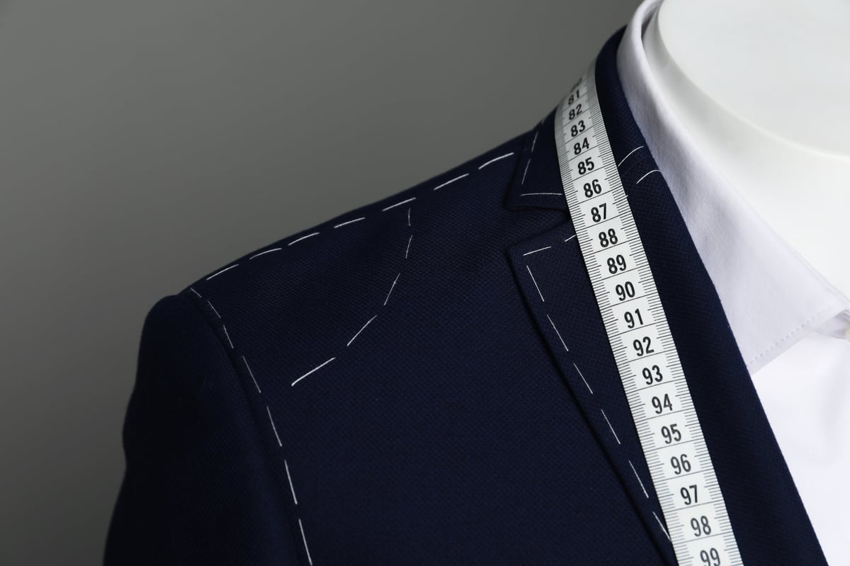 Semi-ready jacket with measuring tape and white shirt on mannequin