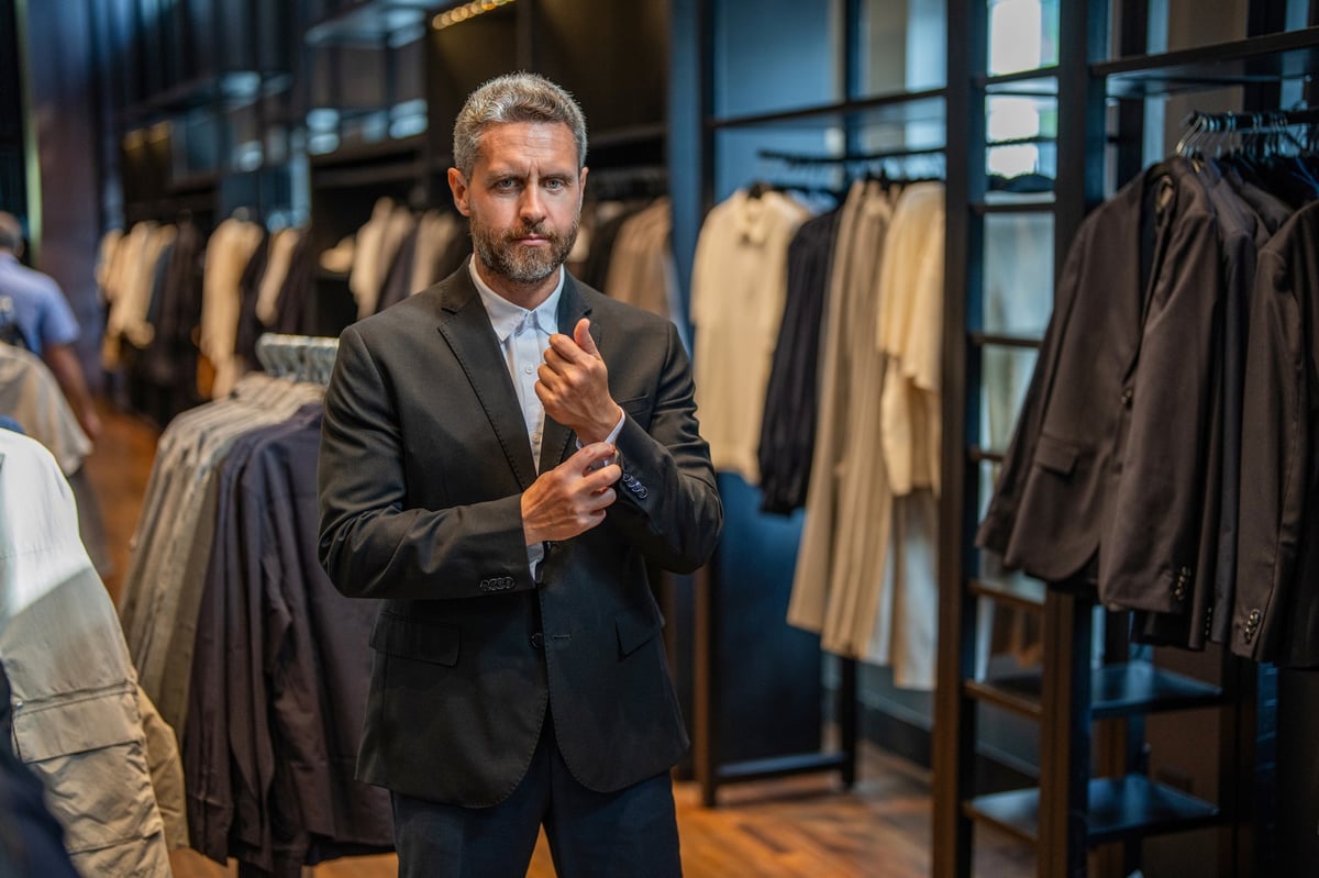 Stylish man being assisted with suit fitting in bespoke tailoring boutique