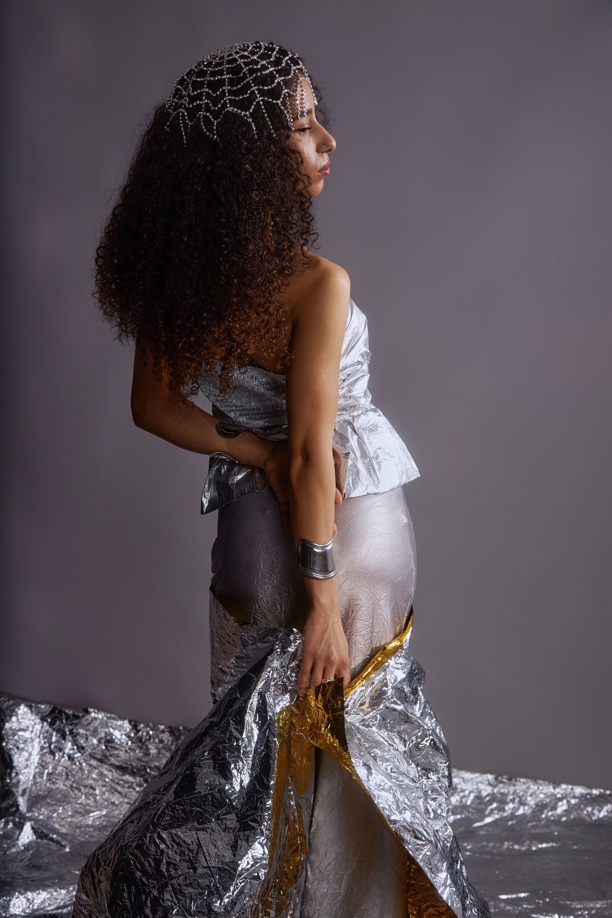 Young woman in metallic couture outfit with decorative headpiece during fashion photoshoot