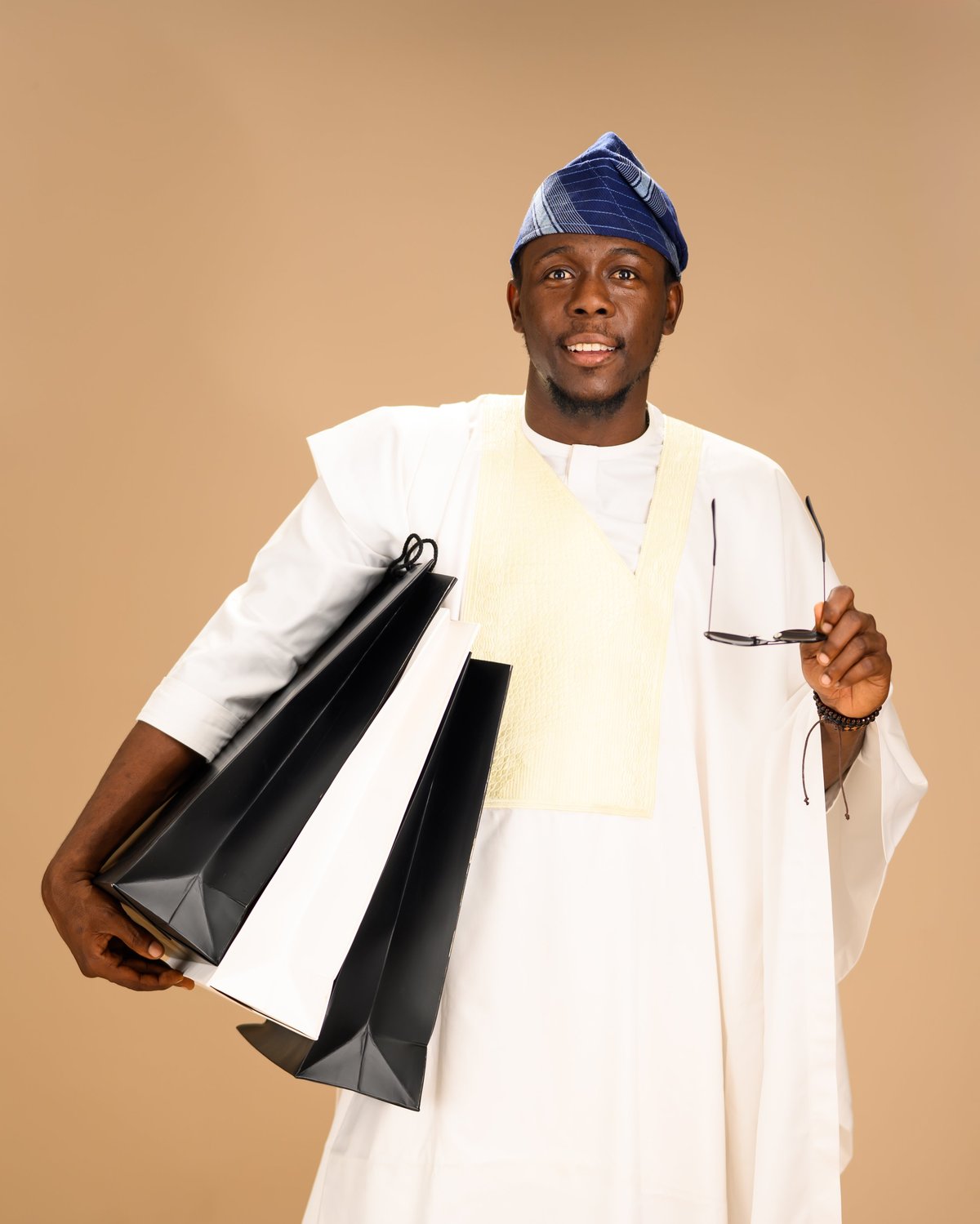Young African man in white agbada with blue cap smiling confidently