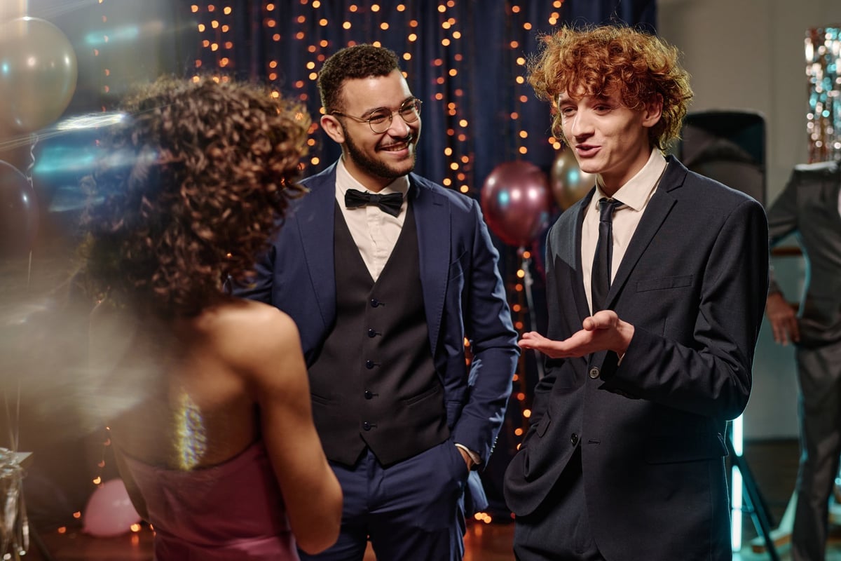 Teen boys in formal suits smiling at festive event with balloons
