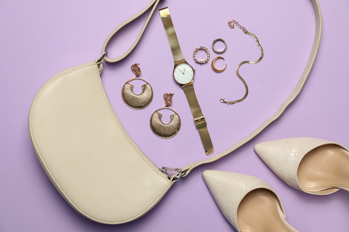 Flat lay composition with golden jewelry shoes and accessories on violet background