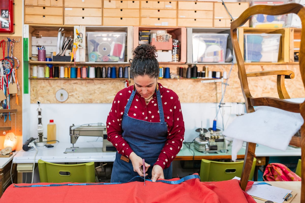 Artisan meticulously cutting fabric with scissors in workshop