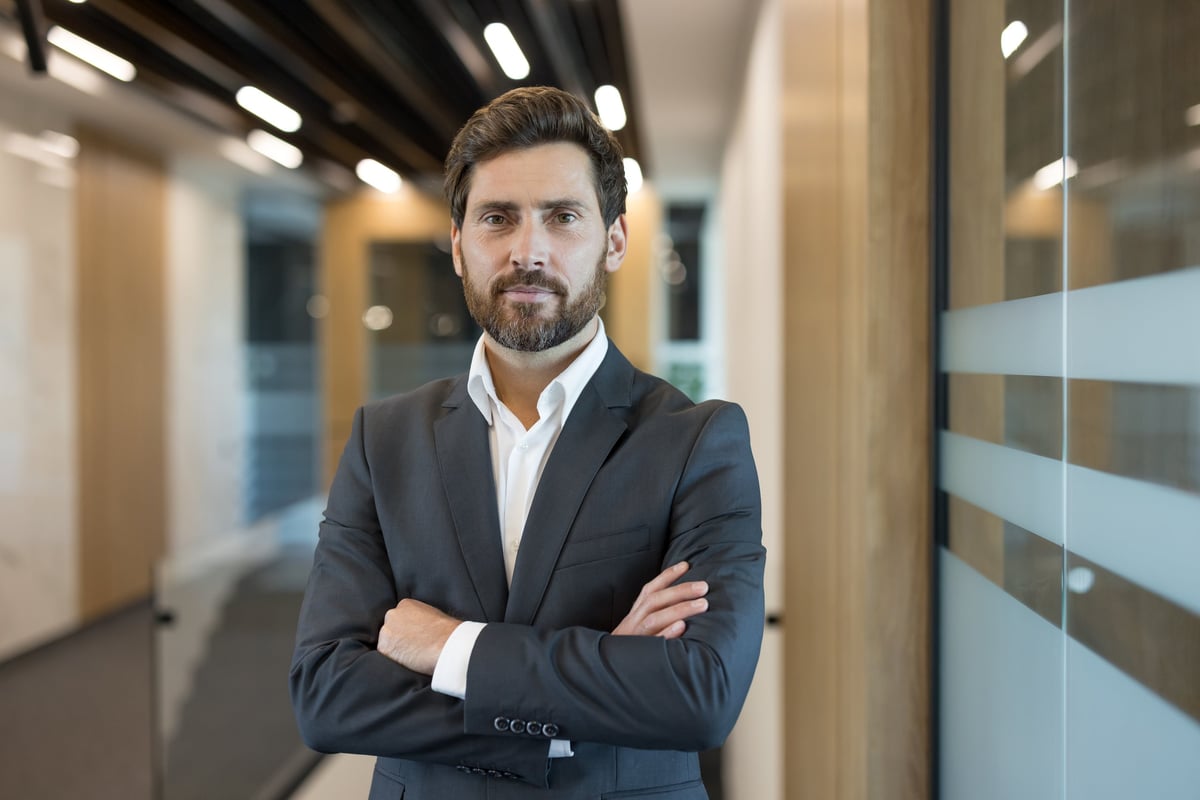 Confident businessman standing with arms crossed in corporate office