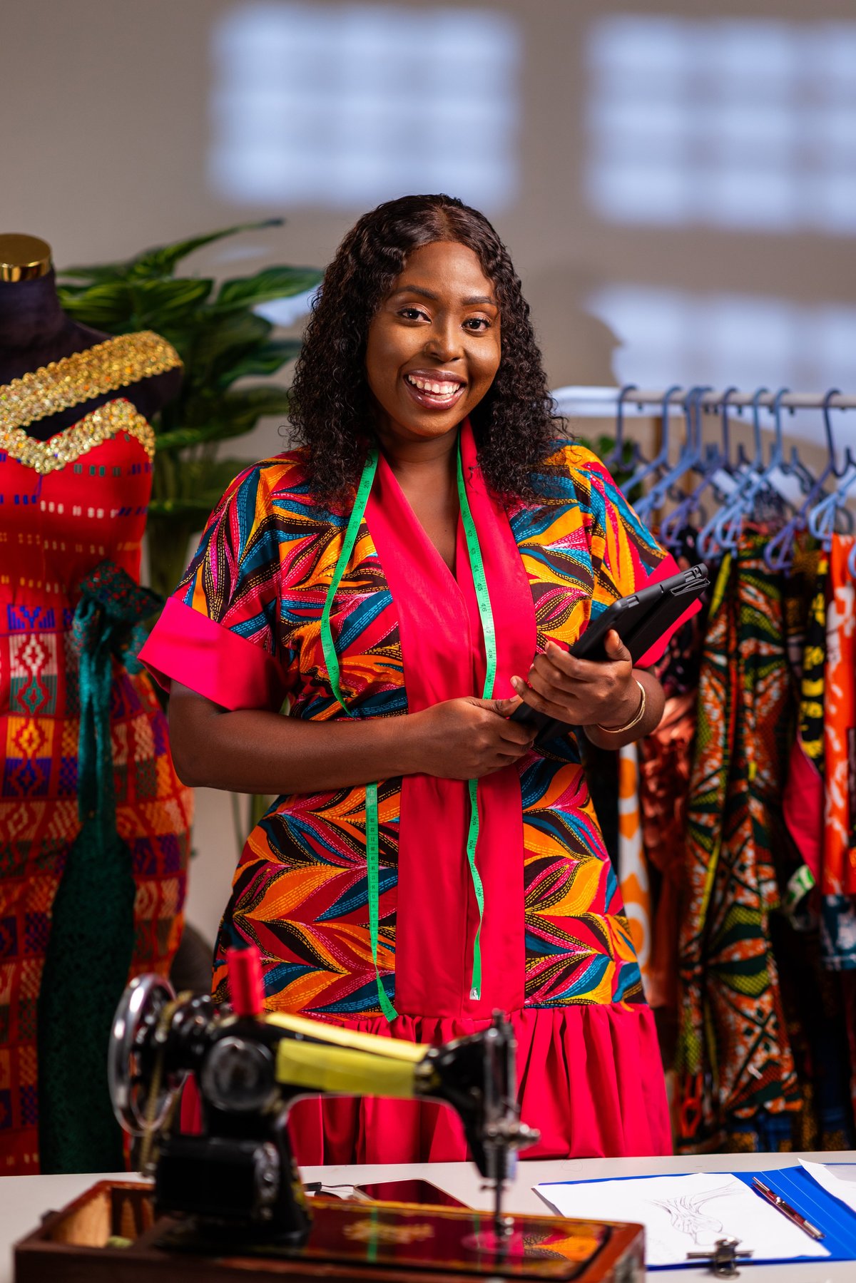 African female fashion designer smiling with tablet in studio