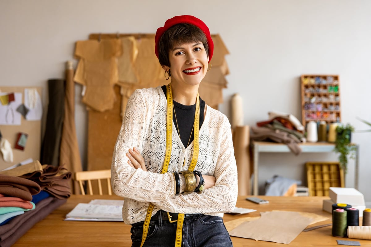 Young fashion designer looking joyful in her fashion design studio